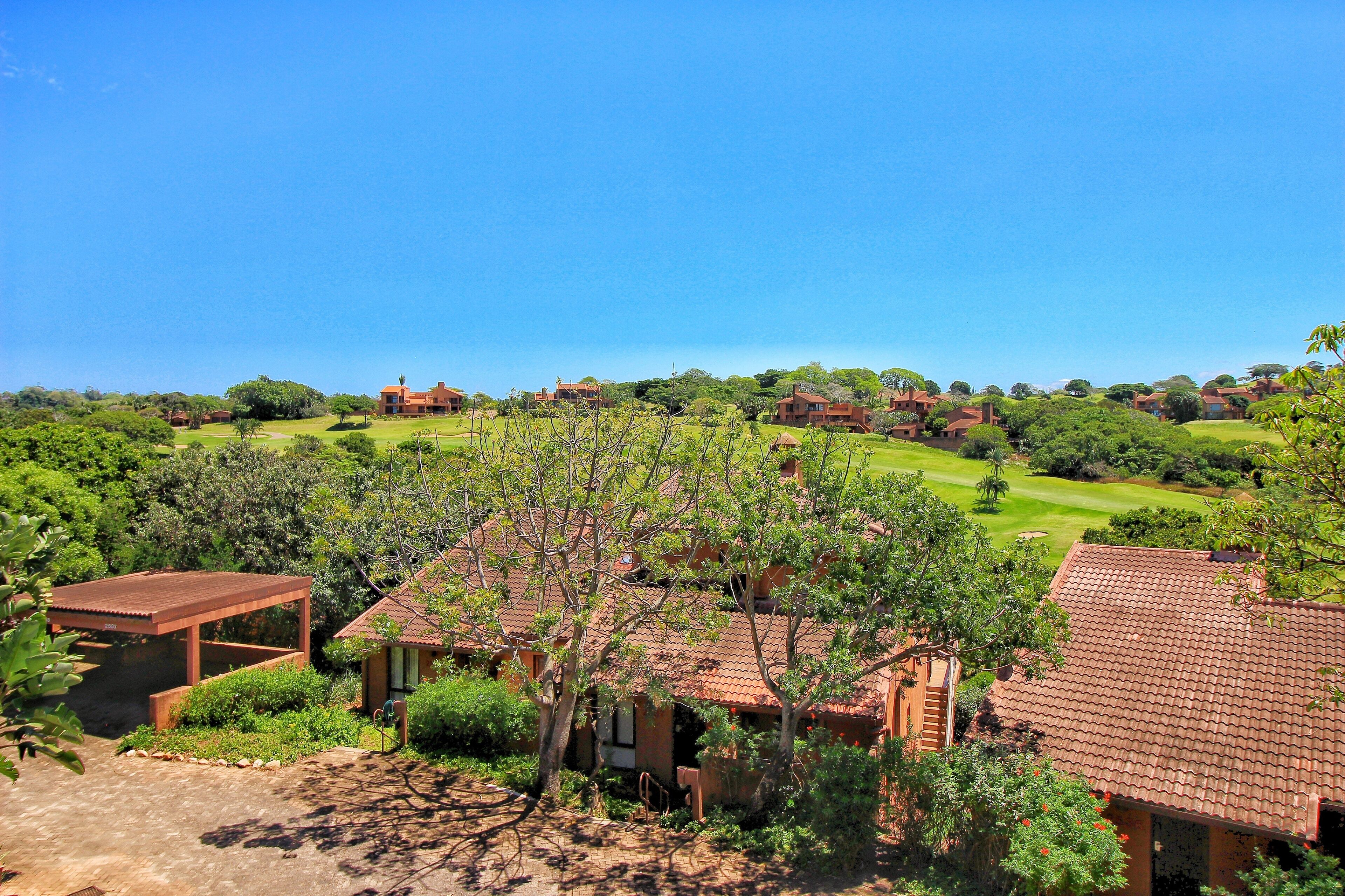 Zona residencial con varias casas, un campo de golf y abundante vegetación.