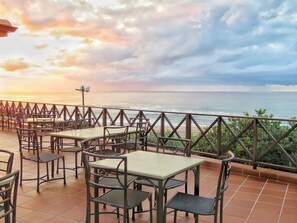 Enjoy ocean views from this tranquil outdoor space, featuring simple tables and comfortable chairs.