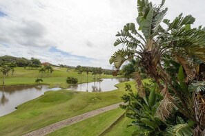Explore the lush golf course surrounded by tropical vegetation and a serene pond.