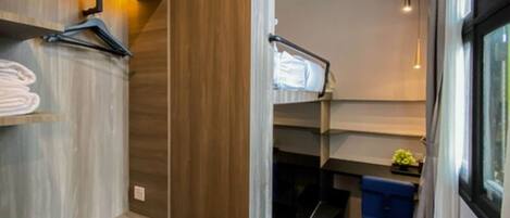 Una habitación de hotel moderna con una litera, estanterías de madera, un escritorio y una ventana con cortinas.