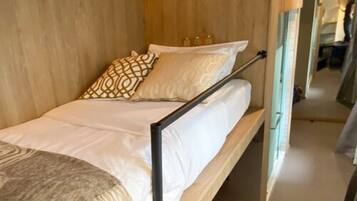 A single bed with a wooden frame, white bedding, and patterned pillows.