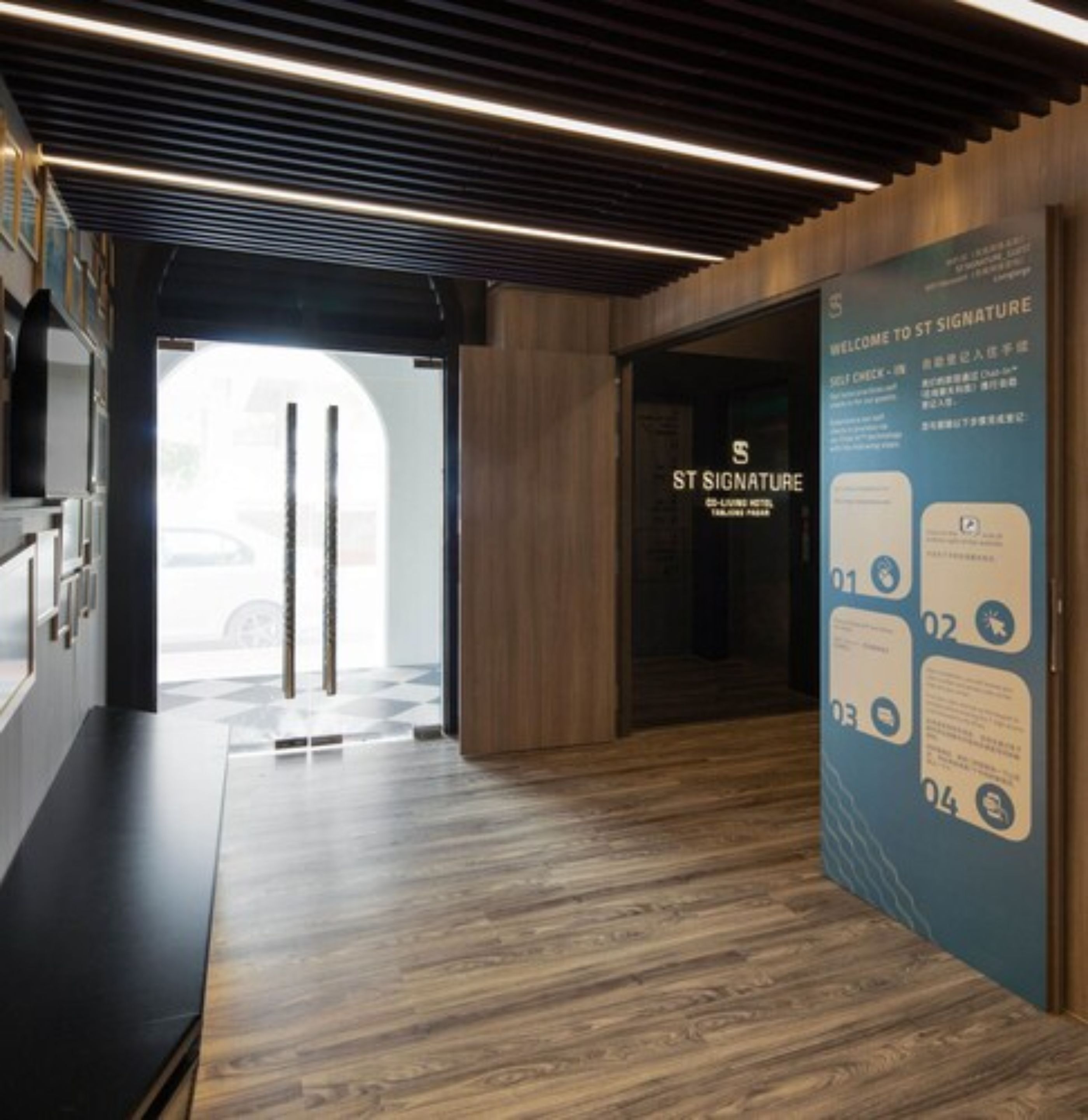 Un vestíbul d'hotel modern amb un paviment de fusta, una taula de recepció i un cartell amb la inscripció "ST SIGNATURE".