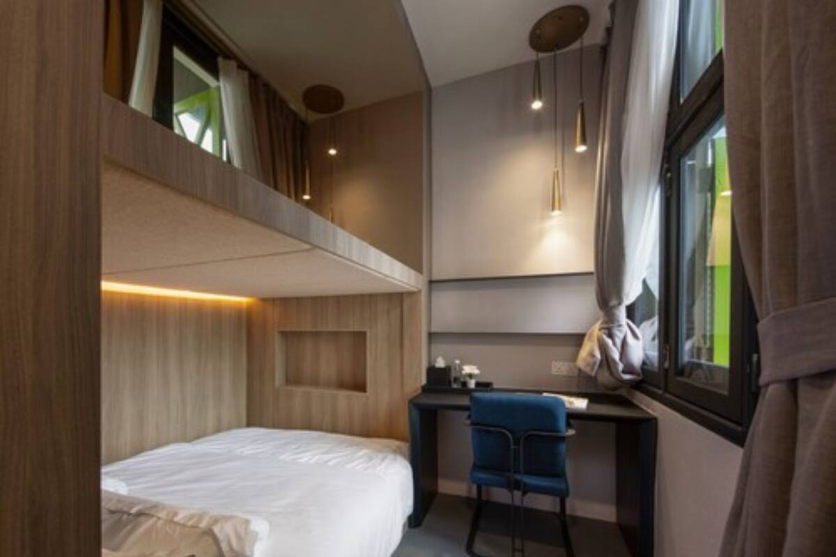 A compact hotel room with a bunk bed, a desk, and a chair.