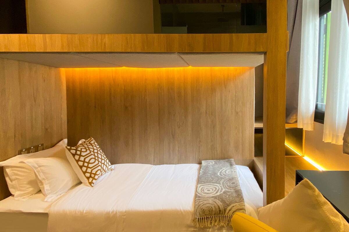 A hotel room with a bunk bed, a sofa, and a bedside table.