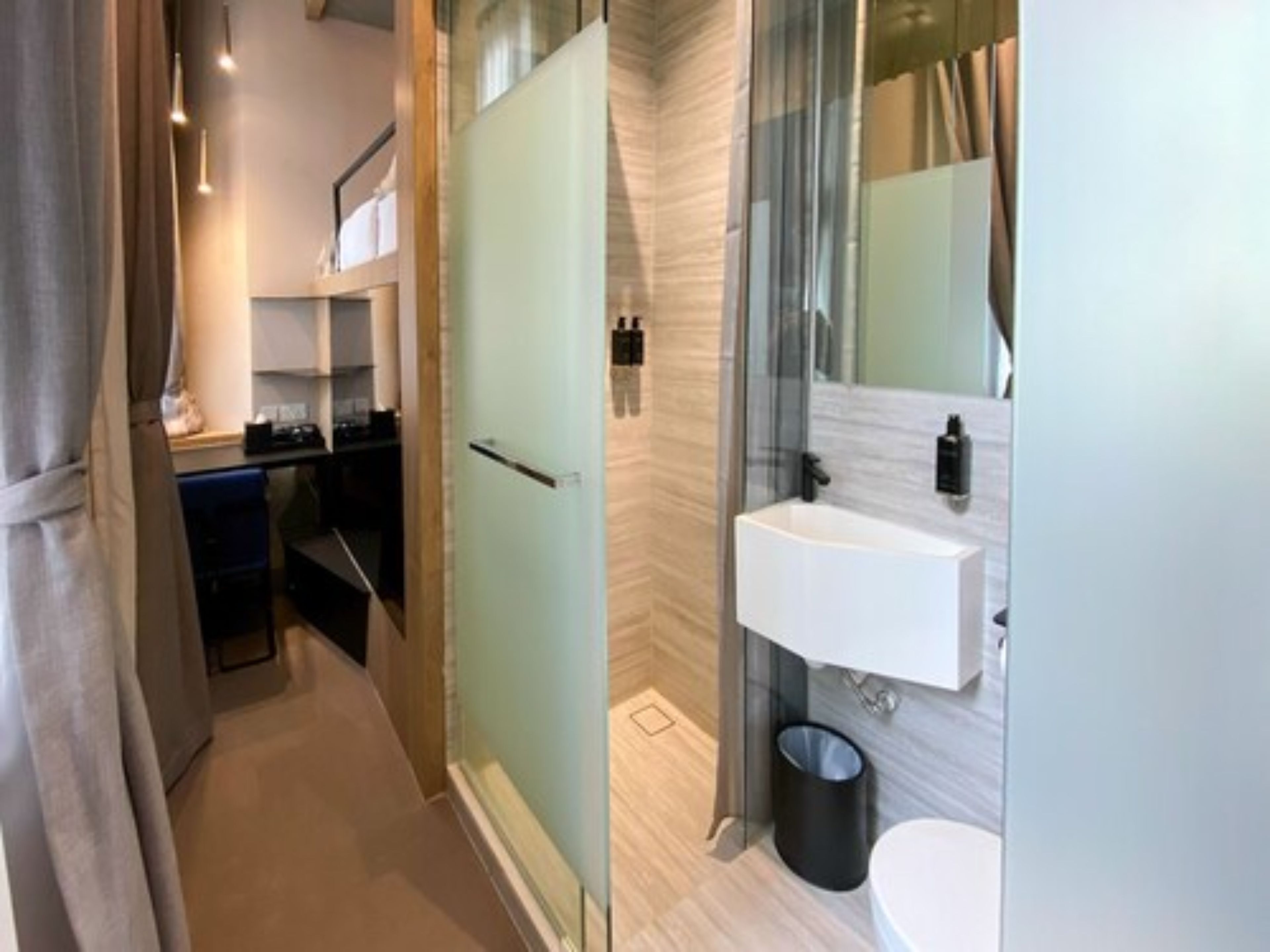 A modern bathroom with a glass shower enclosure, a white sink, and a toilet.