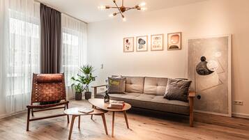 Una sala moderna con un sofá, una mesa de centro de madera, un sillón de cuero y una araña.