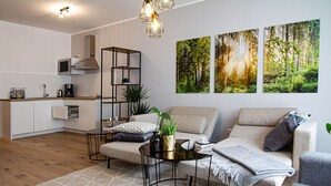 Uma sala de estar moderna com sofá, mesa de centro e área de cozinha com micro-ondas e armários.
