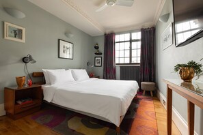 A bedroom with a bed, bedside tables, a desk, a window with curtains, and wall art. - Cockspur Street by Onefinestay (London)