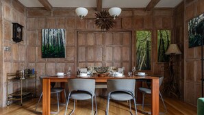 A dining room with a wooden table set for four, surrounded by chairs. There are paintings on the walls depicting forest scenes. - Cockspur Street by Onefinestay (London)