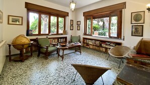 A cozy reading room with large windows, a globe, and bookshelves filled with books. - Dimora Tana Pacenzia (Cefalù)