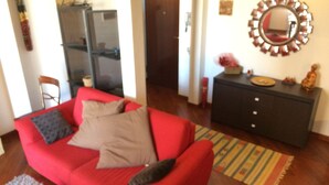 A living room with a red sofa, a dark-colored cabinet, and a mirror on the wall. - Elegante App.to in Centro (Palermo)
