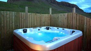 A hot tub with a wooden fence and a mountainous backdrop. - Thurranes guesthouses (Budardalur)