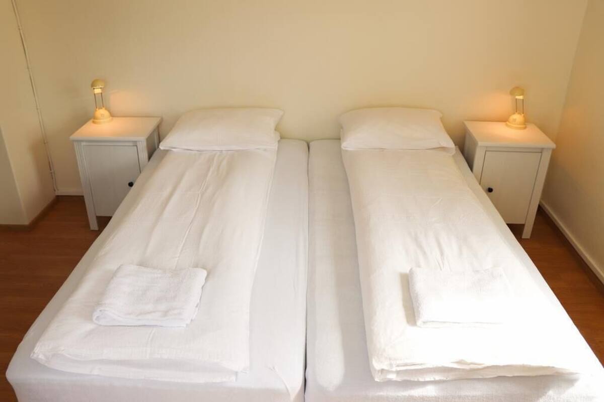 Une chambre double avec deux lits simples, chacun doté d’une table de chevet et d’une lampe.