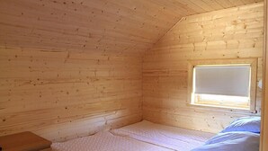 A small, wooden-paneled room with a single bed, a window, and a nightstand. - Thurranes guesthouses (Budardalur)