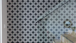 Una escalera moderna con barandas de vidrio y una pared con diseño blanco y negro.