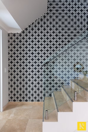 Stunning staircase with a geometric patterned wall and large tile flooring.