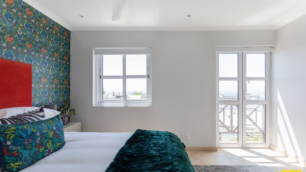Un dormitorio con cama, ventana y balcón.