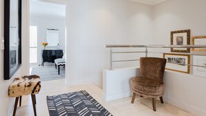 A modern interior with a plush armchair, a patterned rug, and a minimalist decor. - 209 De Waterkant Piazza (Cape Town)