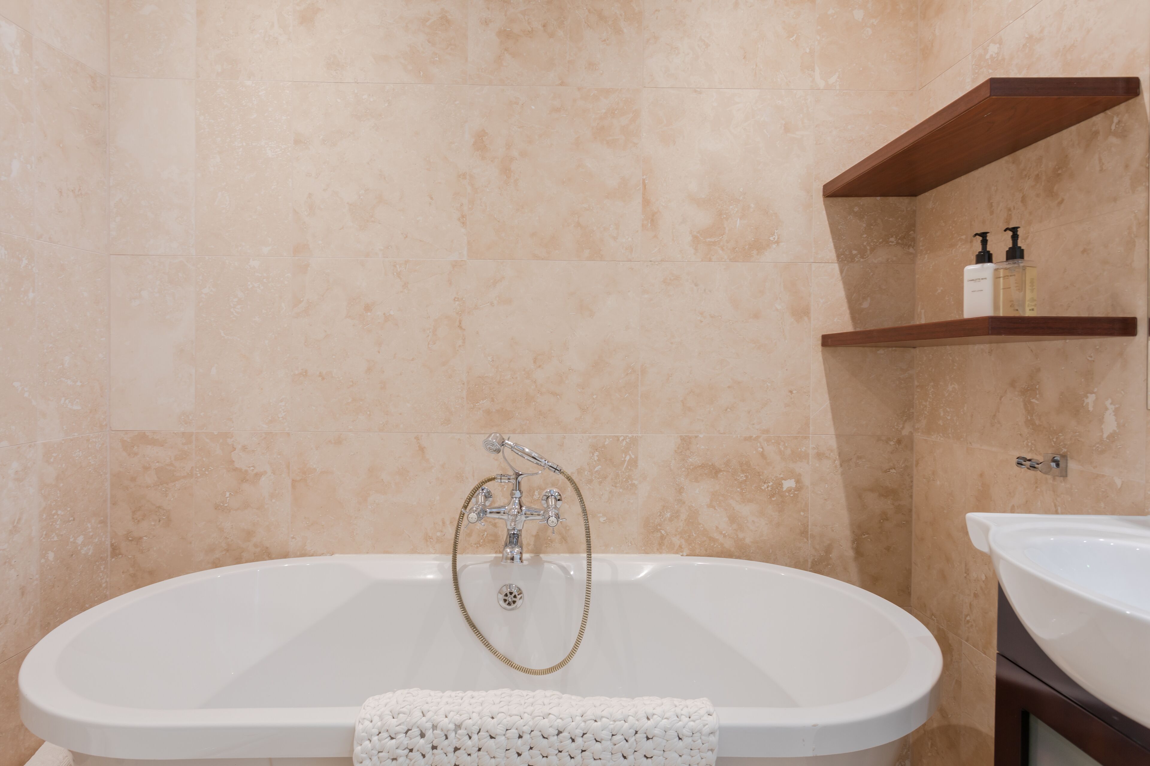 Un bagno con una vasca freestanding, un lavandino e uno scaffale con articoli da toilette.
