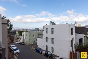 A street view with parked cars, buildings, and a clear sky. - 209 De Waterkant Piazza (Cape Town)