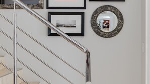 A staircase with a metal railing, a wall with framed artwork, and a mirror. - 209 De Waterkant Piazza (Cape Town)