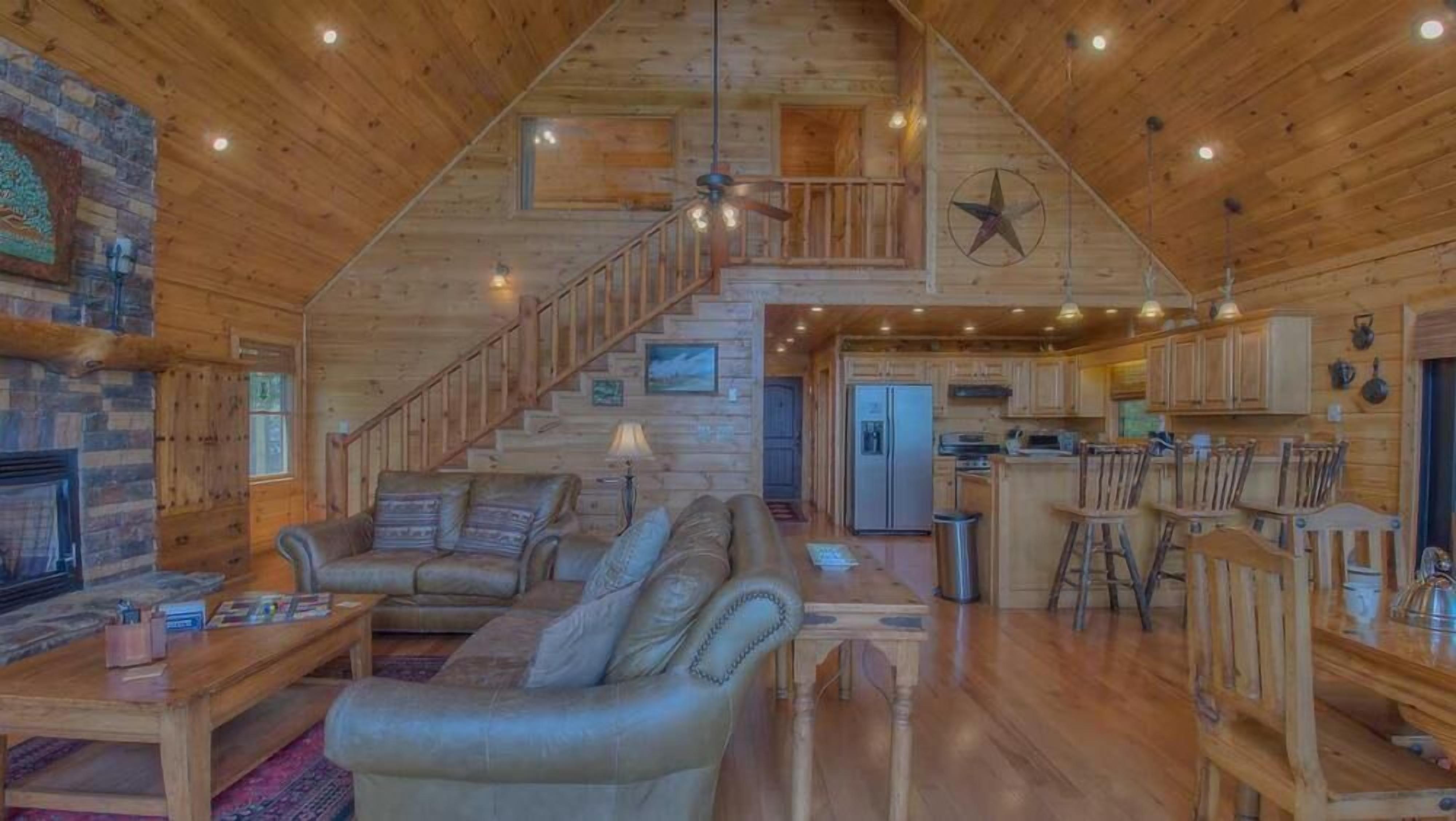 A log cabin interior with a living room, kitchen, and staircase.