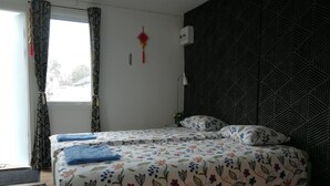 A bedroom with a bed, floral bedding, a patterned wall, and a window with curtains. - Lins B&B (Älvsered)