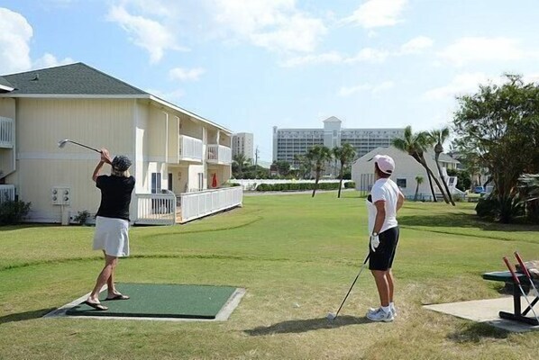 Two people playing golf on a green with a building in the background. - Pet friendly, Water, Water Everywhere SPC4210 (Destin)