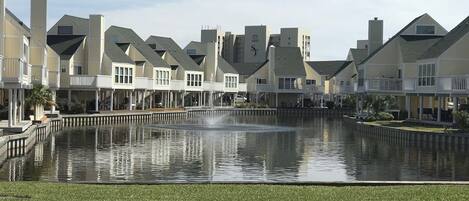 A residential area with houses, a central water feature, and a well-maintained lawn.