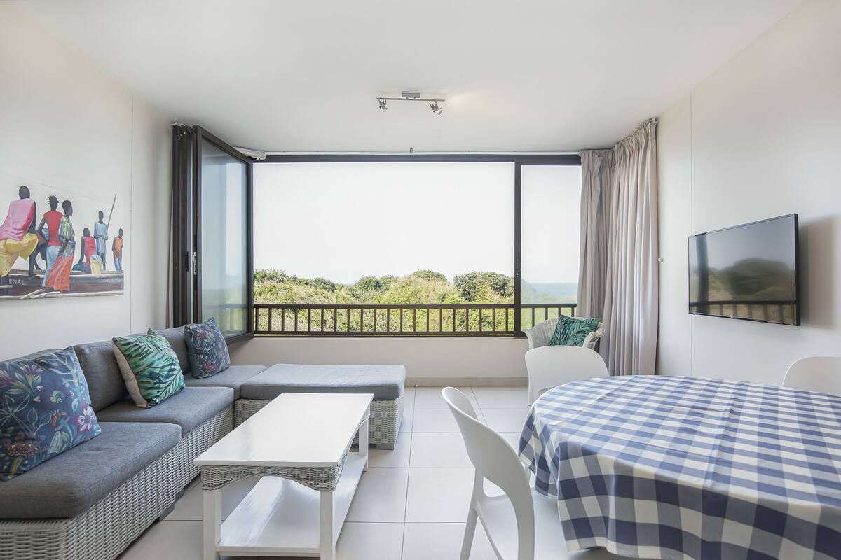 Een moderne kamer met balkon, een bank, een tafel en een televisie.