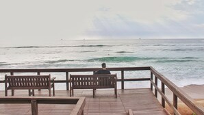 Une jetée en bois avec des bancs d’où l’on peut admirer l’océan.