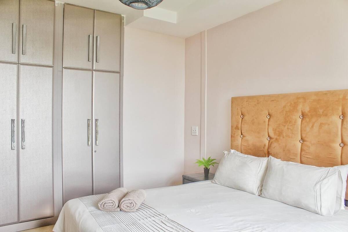 Een slaapkamer met een bed, een hoofdbord, een kledingkast en een kleine plant.