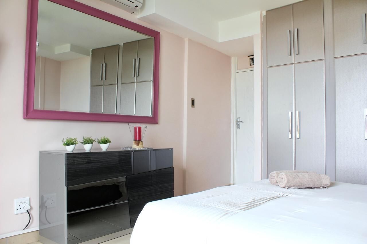 Un dormitorio con cama, cómoda, espejo y armario.