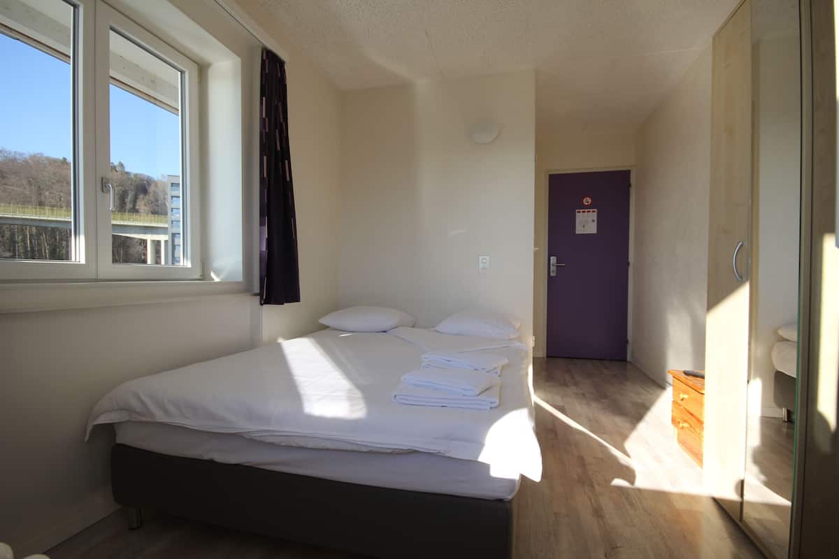 Un dormitorio con cama, ventana y puerta.