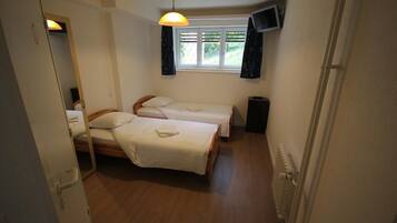 A small, clean room with two single beds, a TV, and a window with curtains.