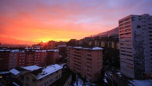A cityscape at sunset with high-rise buildings, one featuring a large mural. - Hotel Abaca (Vevey)