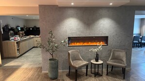 A modern interior with a stone fireplace, two armchairs, a small table, and a potted plant.