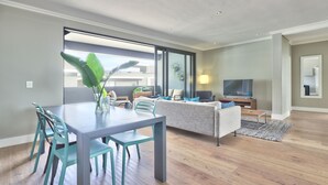 Una sala de estar moderna con comedor, ventanas amplias y un televisor de pantalla plana.
