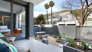 Un patio exterior moderno con mesa de comedor, asientos y macetas.