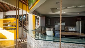 Eine moderne Küche mit einer Glasinsel, dunklen Holzschränken und einem Edelstahlkühlschrank.