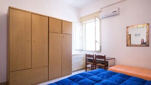 A bedroom with a large wardrobe, a desk, and a bed.
