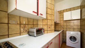 Una cocina funcional con estufa a gas, tostadora y lavadora.