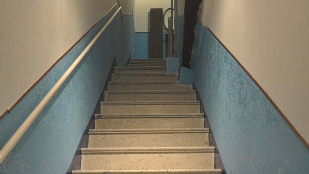 Una escalera con barandilla que lleva a un rellano con una lámpara.