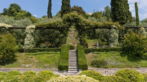 Un jardin agrémenté d’un escalier en pierre menant à une porte, entouré de différentes espèces de plantes et d’arbres.