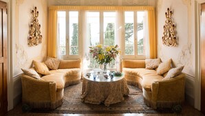 Une pièce avec une table ronde, deux canapés et une fenêtre avec des rideaux.