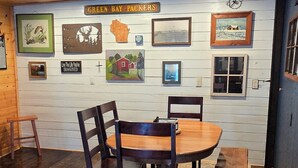 Een eethoek met een houten tafel en stoelen, een bankje, een vloerkleed en kunstwerken aan de muur.