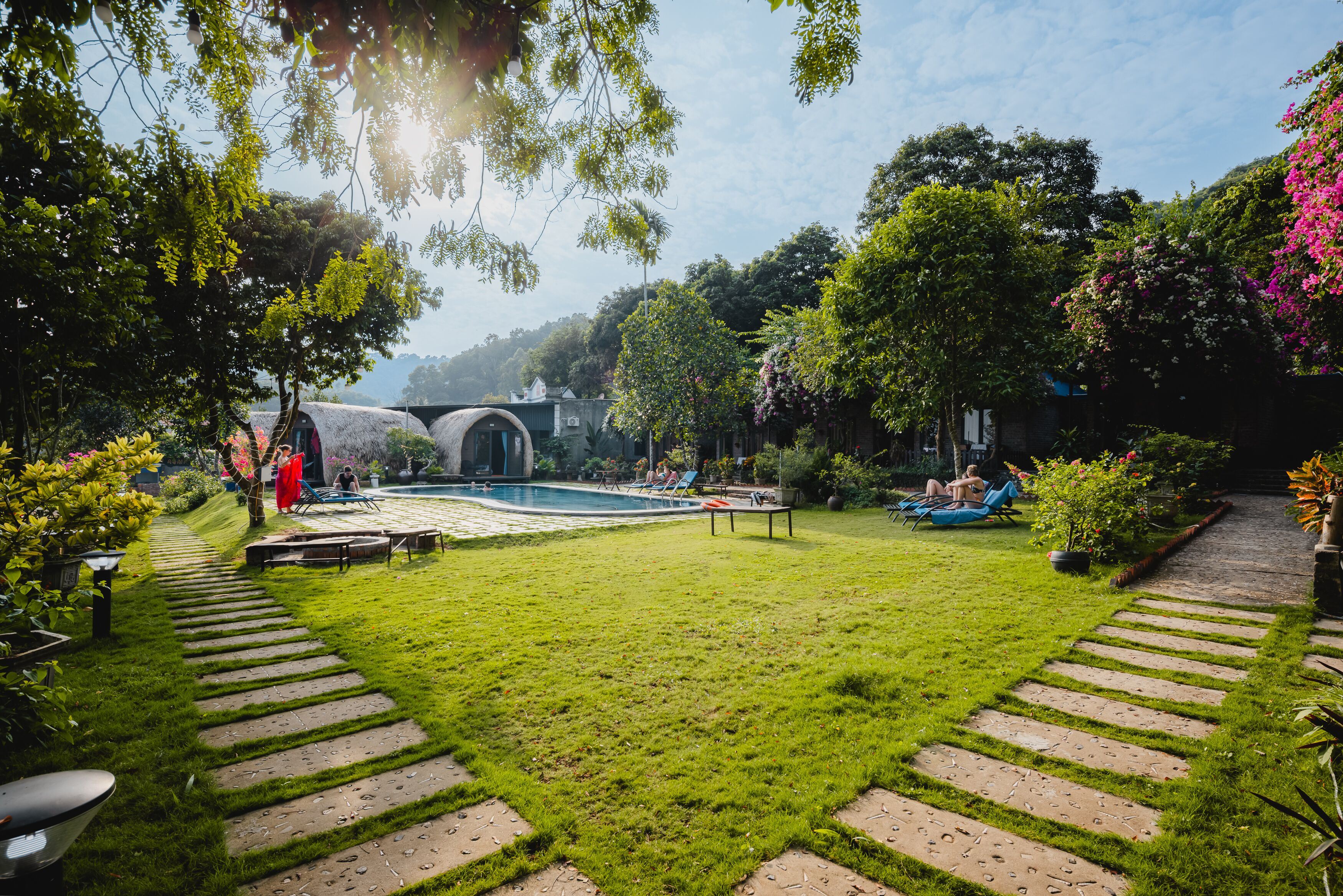 Un jardín bien cuidado con piscina, senderos de piedra y abundante vegetación.