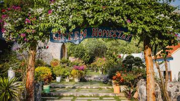 A garden entrance with a sign reading "Green Homestay" and stone steps leading up to it.