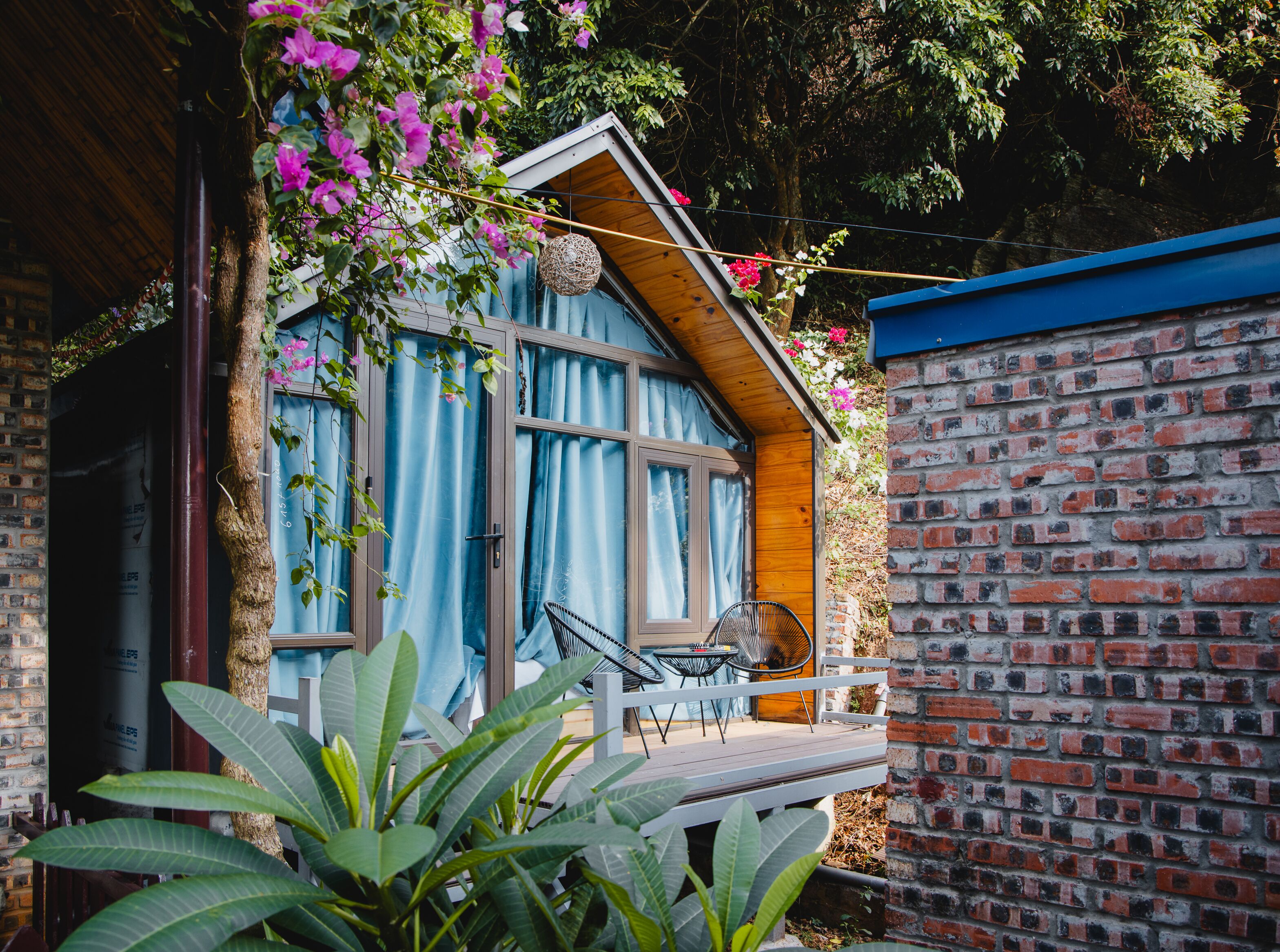 A wooden house with a balcony, a brick wall, and a hanging basket.