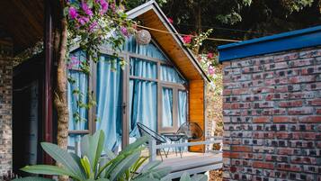 A wooden house with a balcony, a brick wall, and a hanging basket.